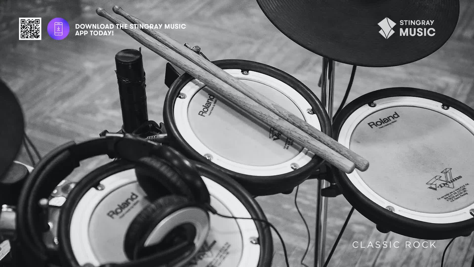 A pair of drumsticks rests casually on a Roland drum pad. The setup, framed by a cymbal and headphones, suggests a connection to Stingray Classic Rock from Canada.
