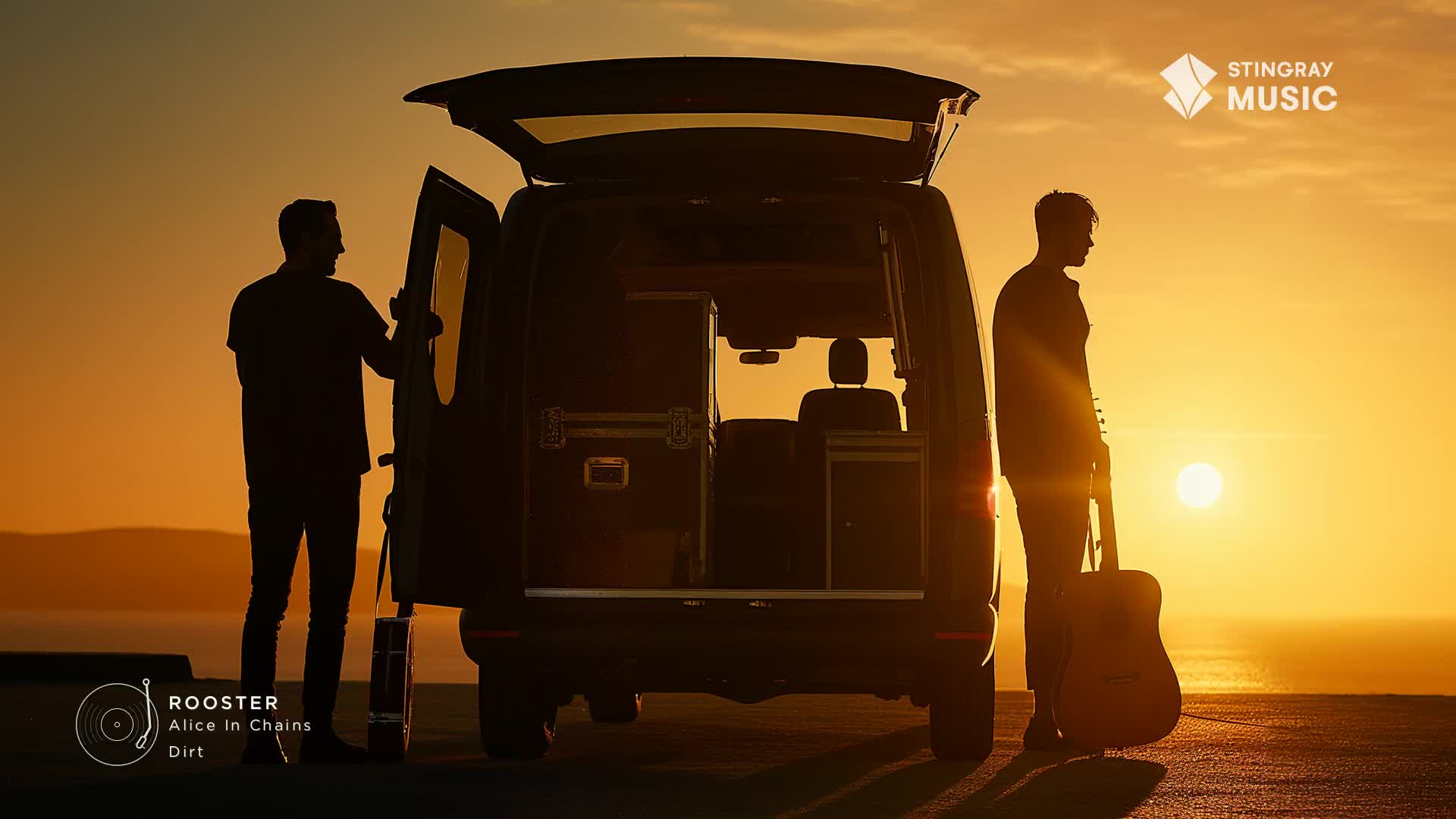 The sun dips low over the ocean, casting a warm glow as two men stand by a van, its back doors open. One man leans against the open door, while the other holds a guitar, ready for a Stingray Classic Rock performance somewhere in Canada.