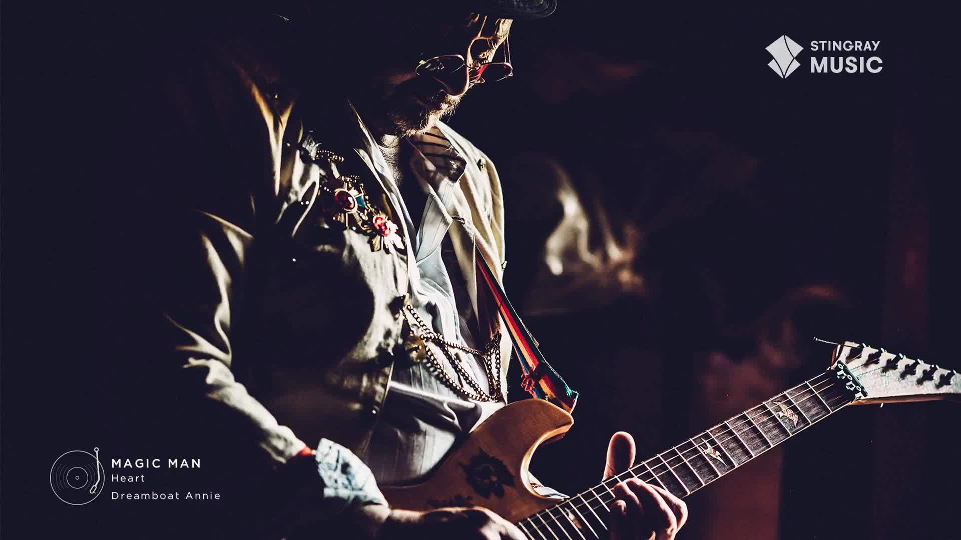 A musician in a decorated jacket plays a guitar, the headstock of which bears a striking pattern. The Stingray Classic Rock logo is visible in the upper right corner.