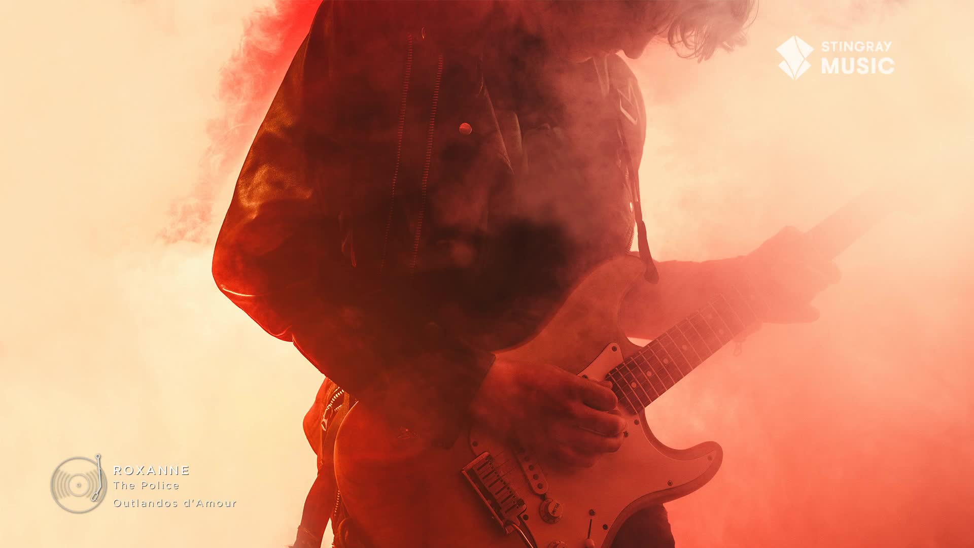 A guitarist plays a white Fender Stratocaster, bathed in an intense red haze. The air is thick with smoke, obscuring much of the performer as they launch into "Roxanne" by The Police.