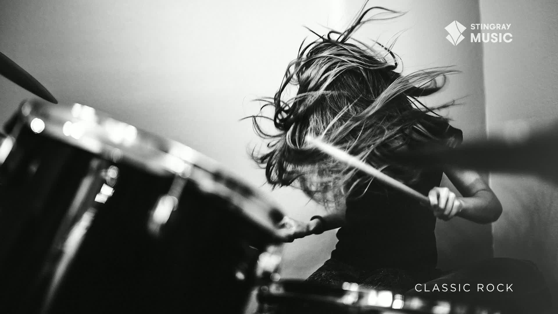 A drummer's hair flies everywhere as they pound out a beat on the drums, the sound of classic rock filling the air. This is the raw energy of a Canadian band in full swing.
