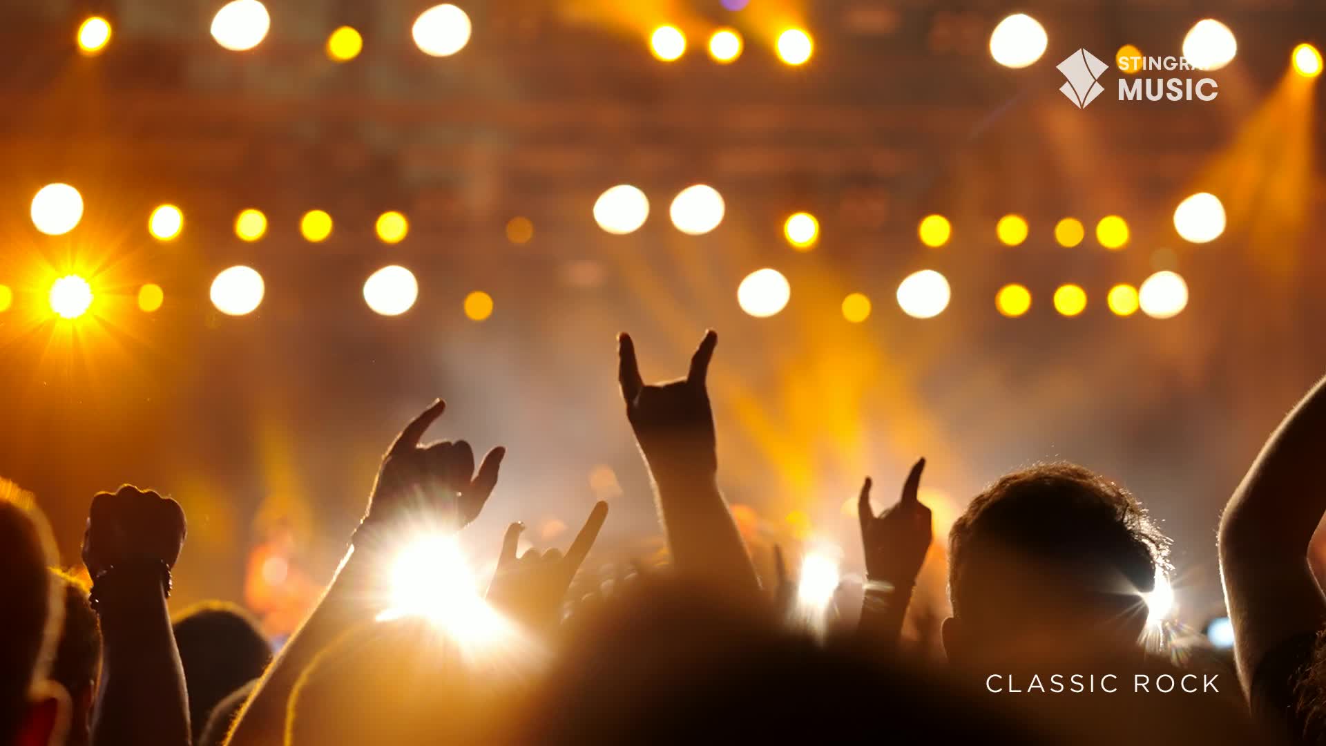 Hands are raised, some forming the devil horns, in a crowd bathed in warm stage lights. The air vibrates with the energy of a classic rock show in Canada.