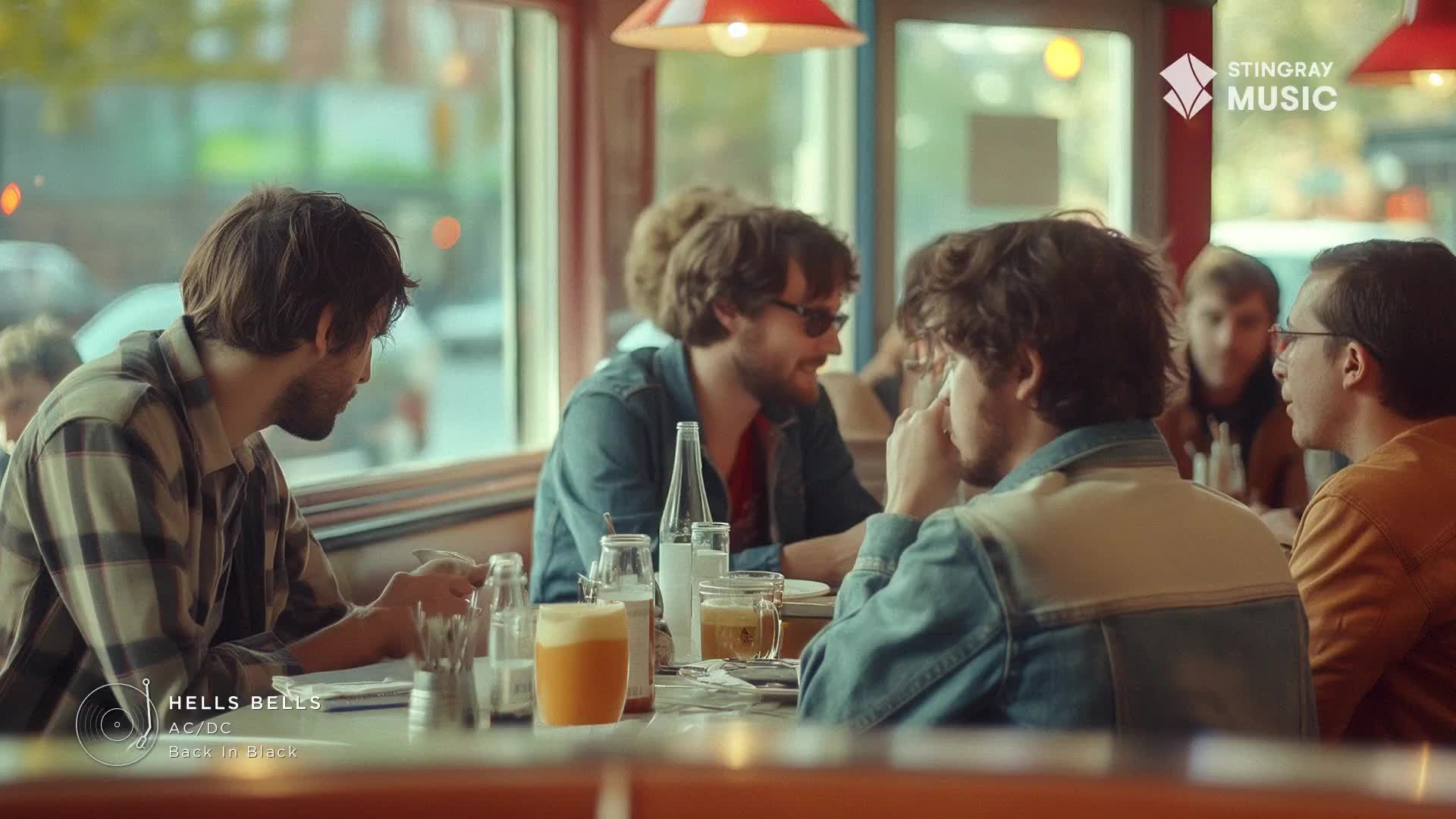 The guys are gathered around a diner table, the scent of AC/DC's "Hells Bells" filling the air. A pint of amber beer sits beside a bottle of water, waiting to be enjoyed with their classic rock soundtrack.