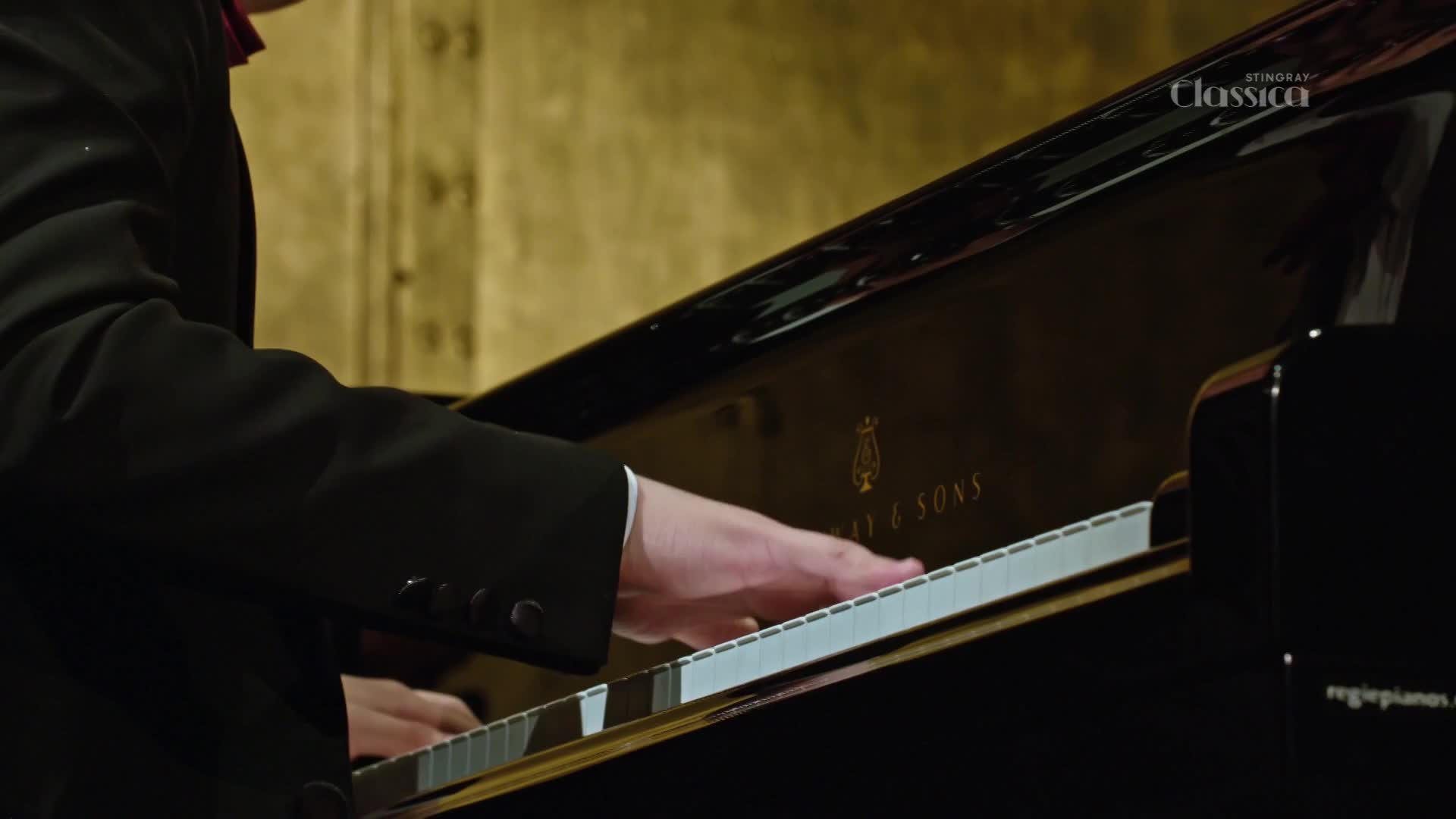 A pianist's hands dance across the keys of a Steinway, the black lacquer reflecting the warm light. The Stingray Classica logo is visible in the corner, suggesting a recording from Canada.
