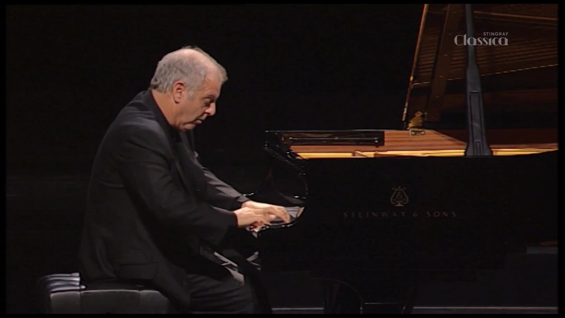 A man in a dark suit sits at a grand piano, his fingers dancing across the keys. The Stingray Classica logo is visible in the corner, and the Steinway & Sons logo is on the piano.
