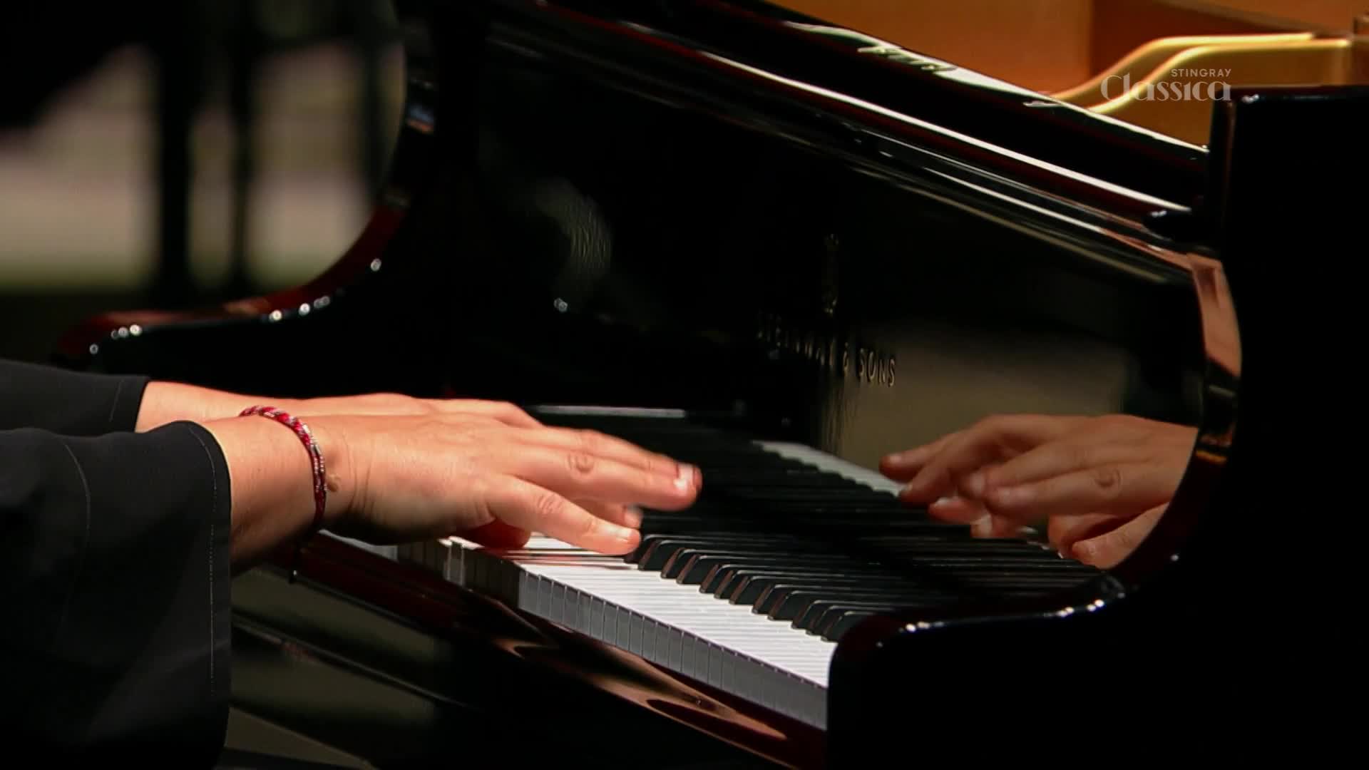 Fingers dance across the black and white keys of a grand piano. The polished wood gleams under the stage lights as the music fills the hall. Fingers dance across the black and white keys of a grand piano. The polished wood gleams under the stage lights as the music fills the hall.