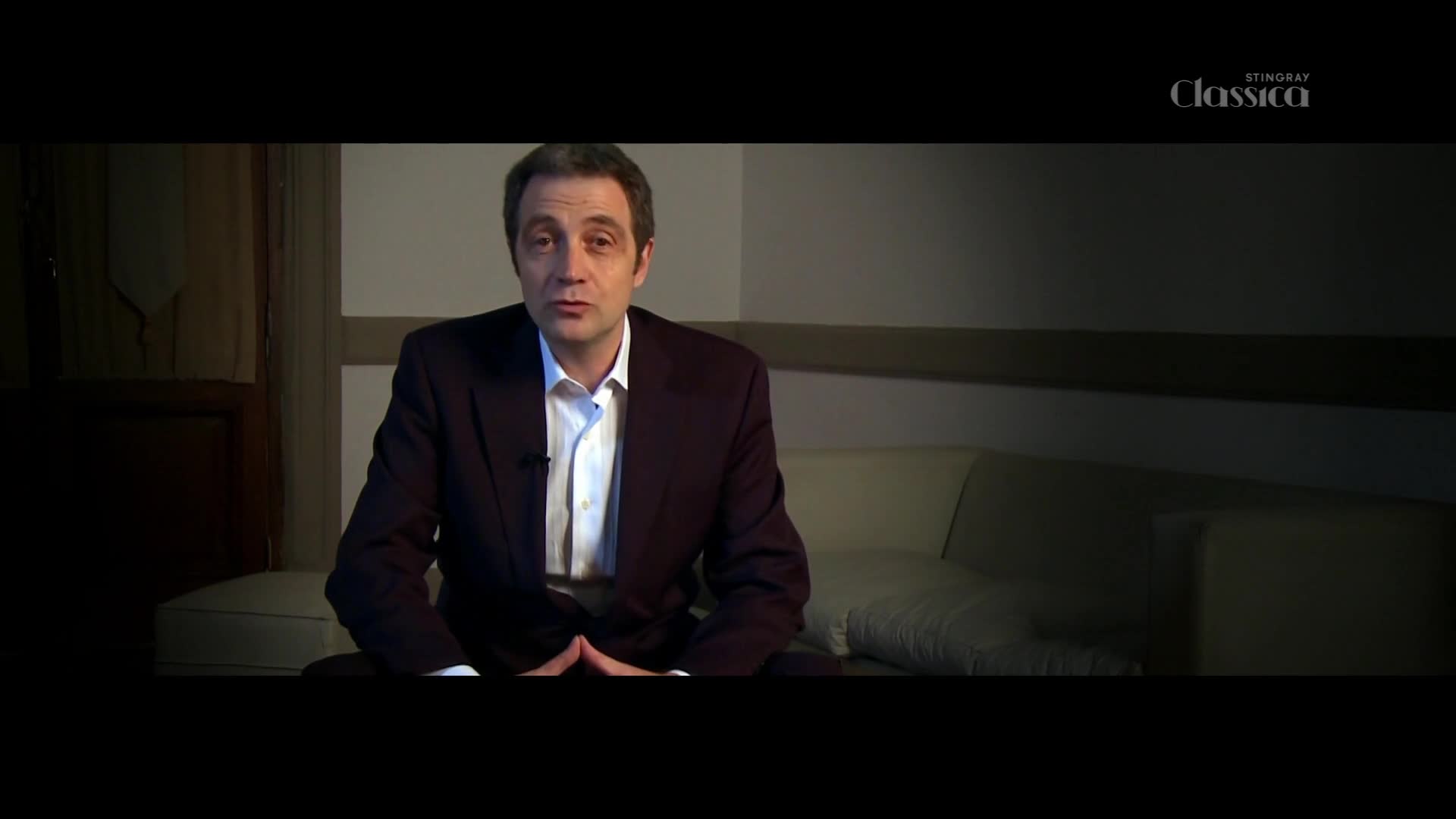 A man in a dark suit and white shirt speaks directly to the camera. A Stingray Classica logo appears in the upper right corner.