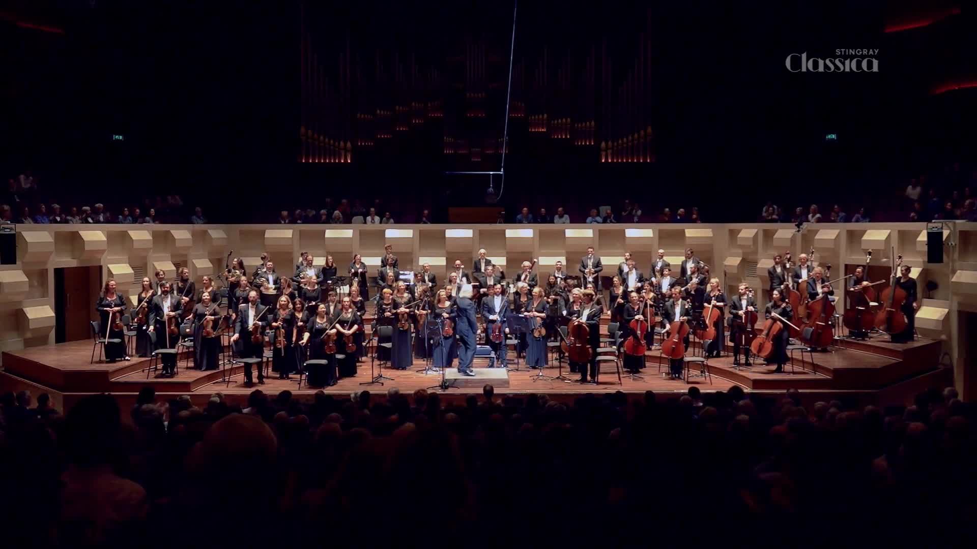 The conductor steps onto the podium as the orchestra tunes their instruments. A sea of musicians, dressed in formal attire, are ready to perform for the Stingray Classica broadcast.