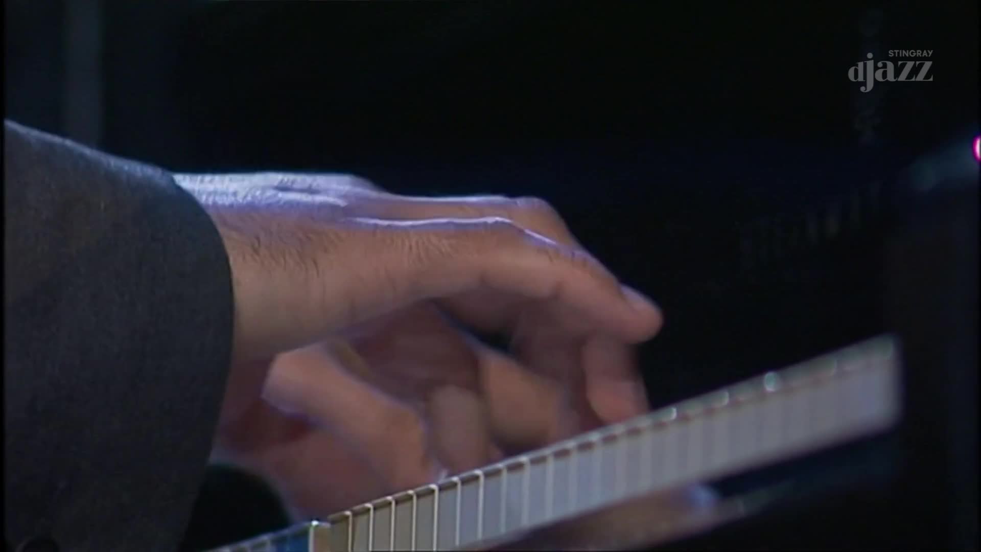 Fingers dance across the keys, pressing down with precision. The musician's hand, illuminated by the stage lights, is the focus of the Stingray DJAZZ performance.
