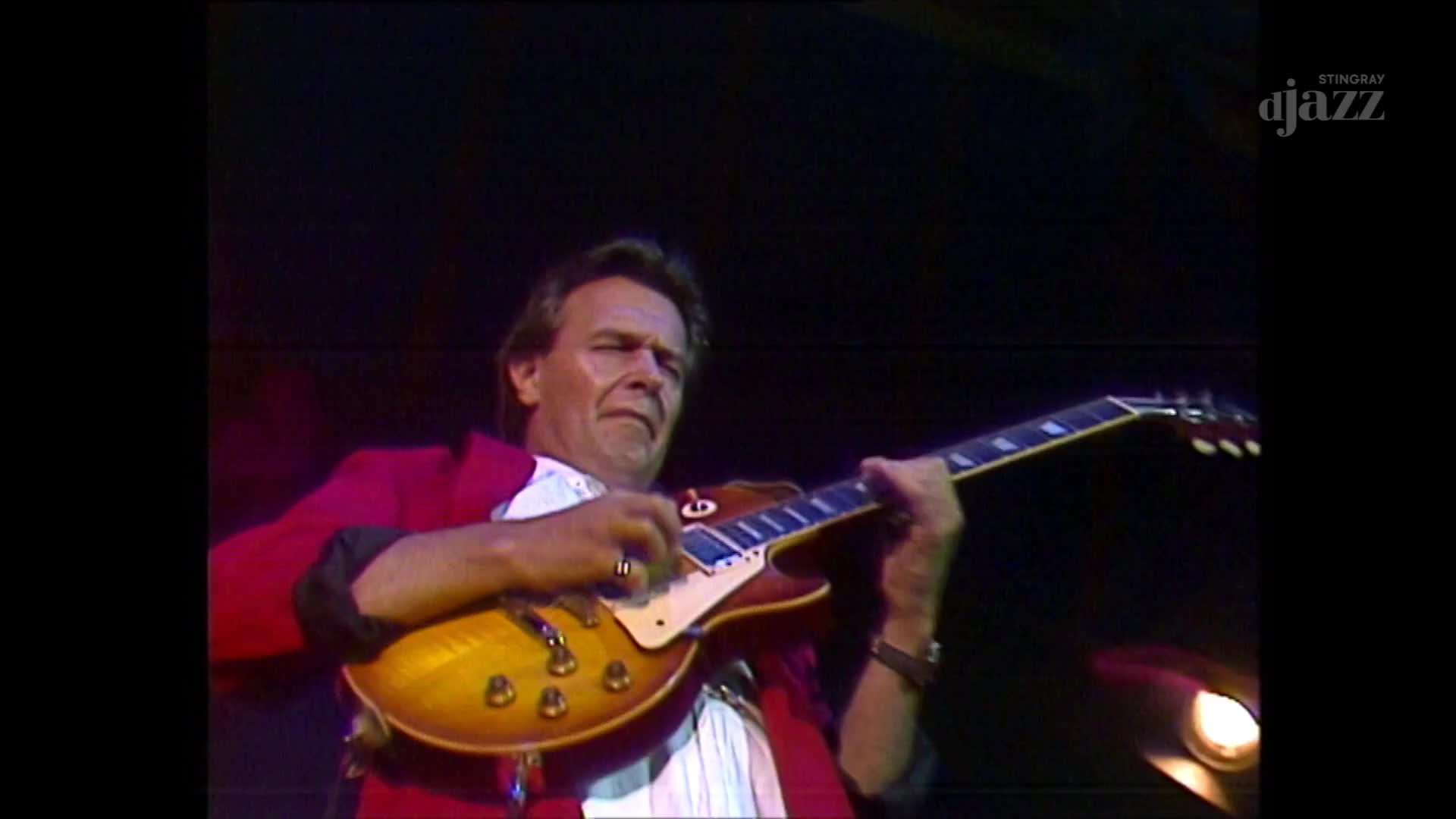 The guitarist, wearing a red jacket, strums his sunburst-colored instrument with focused intensity. It's a live performance, likely from Canada, broadcast by Stingray DJAZZ.
The guitarist, wearing a red jacket, strums his sunburst-colored instrument with focused intensity. It's a live performance, likely from Canada, broadcast by Stingray DJAZZ.