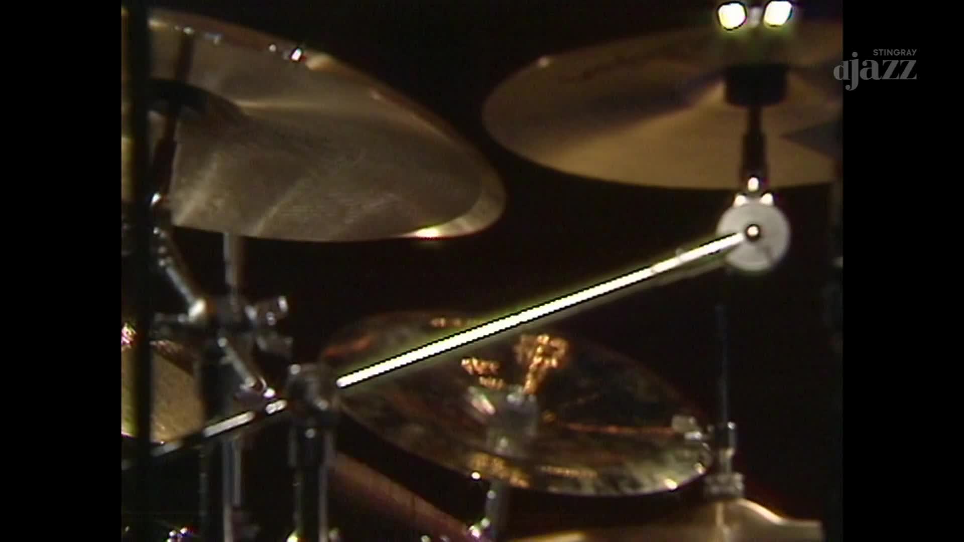 A drumstick is poised, ready to strike the cymbal. The warm glow of stage lights catches the brass, hinting at the Stingray DJAZZ performance. A drumstick is poised, ready to strike the cymbal. The warm glow of stage lights catches the brass, hinting at the Stingray DJAZZ performance.