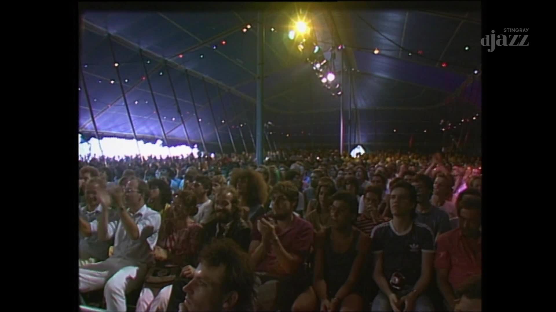The crowd inside this Canadian tent is clapping, a wave of hands rising and falling under the colorful lights. A Stingray DJAZZ logo appears in the corner, marking the broadcast.