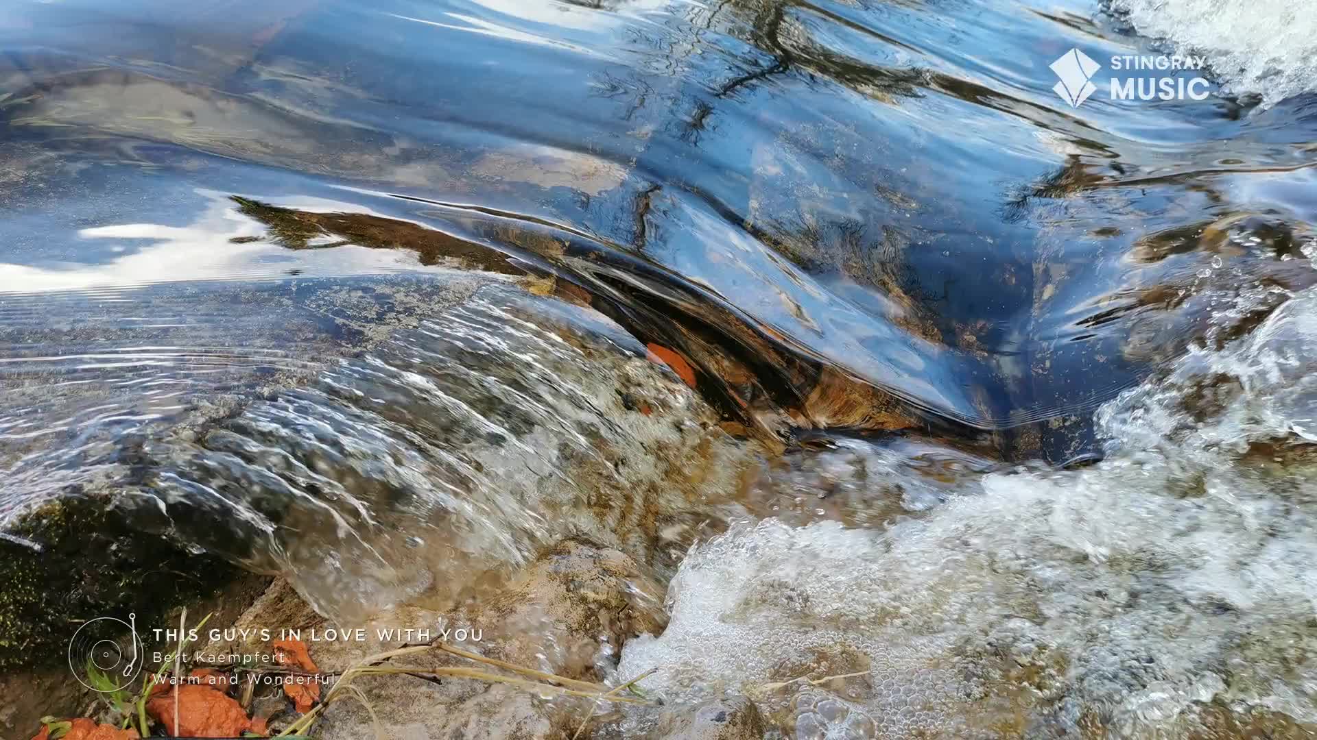 Water rushes over a small ledge, the surface reflecting the sky. The Stingray Music logo sits in the corner, a gentle soundtrack for this Canadian stream.
