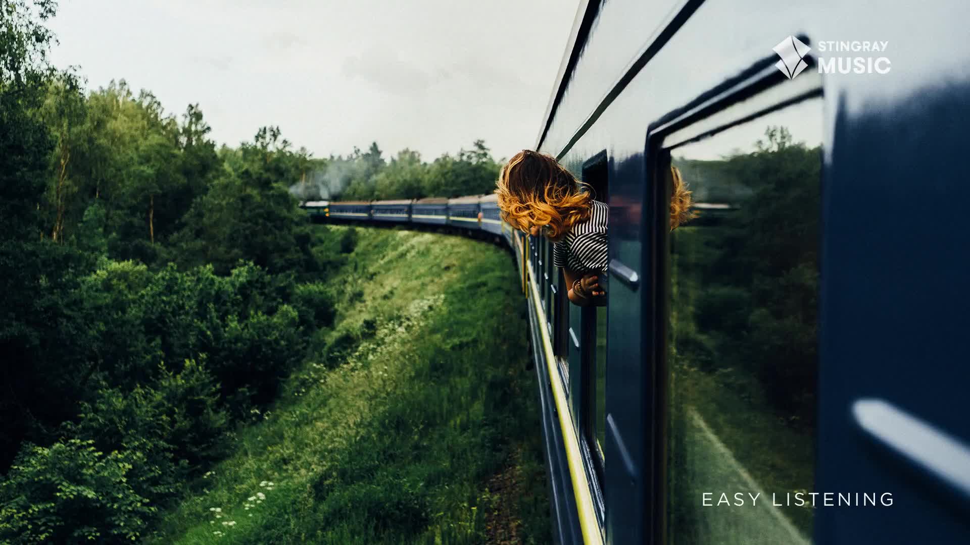 A train, its windows reflecting the landscape, snakes along a green, tree-lined track.  Someone leans out, hair blowing, as the train, perhaps on a journey through Canada, cruises along, the perfect soundtrack for Stingray Easy Listening.
