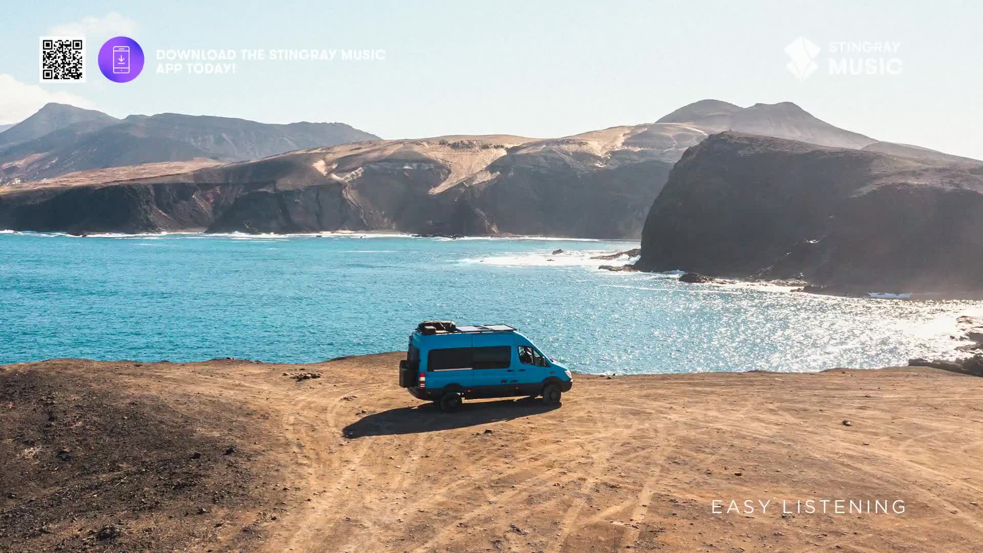 A blue van sits parked on a dirt track, overlooking the ocean. The scene feels peaceful, like something you'd hear on Stingray Easy Listening, a perfect soundtrack for a Canadian road trip.
