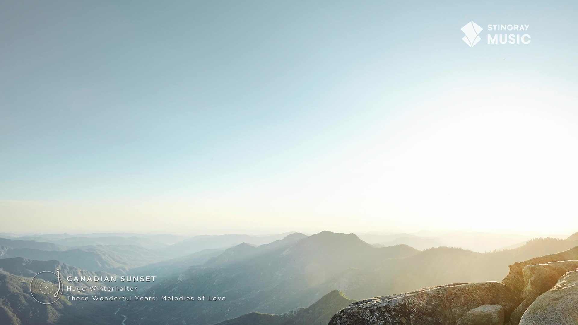 The sky is a gradient of blues, fading into the bright sun that's just beyond the mountain peaks. Below, the landscape rolls out, a hazy panorama that feels like it could be a Stingray Easy Listening album cover.
