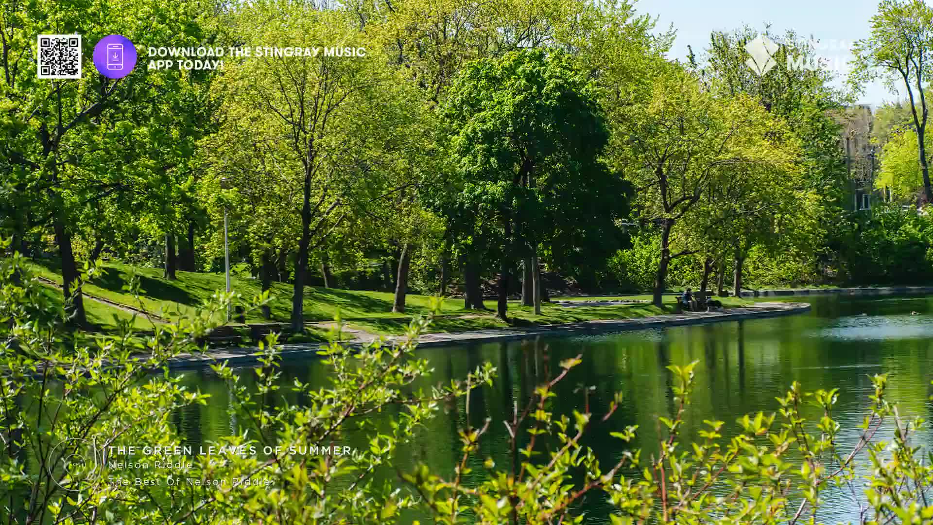 Sunlight streams through the lush green trees lining the water's edge. A gentle breeze rustles the leaves as a Stingray Easy Listening tune plays in the background, perfect for a relaxing afternoon in Canada.
