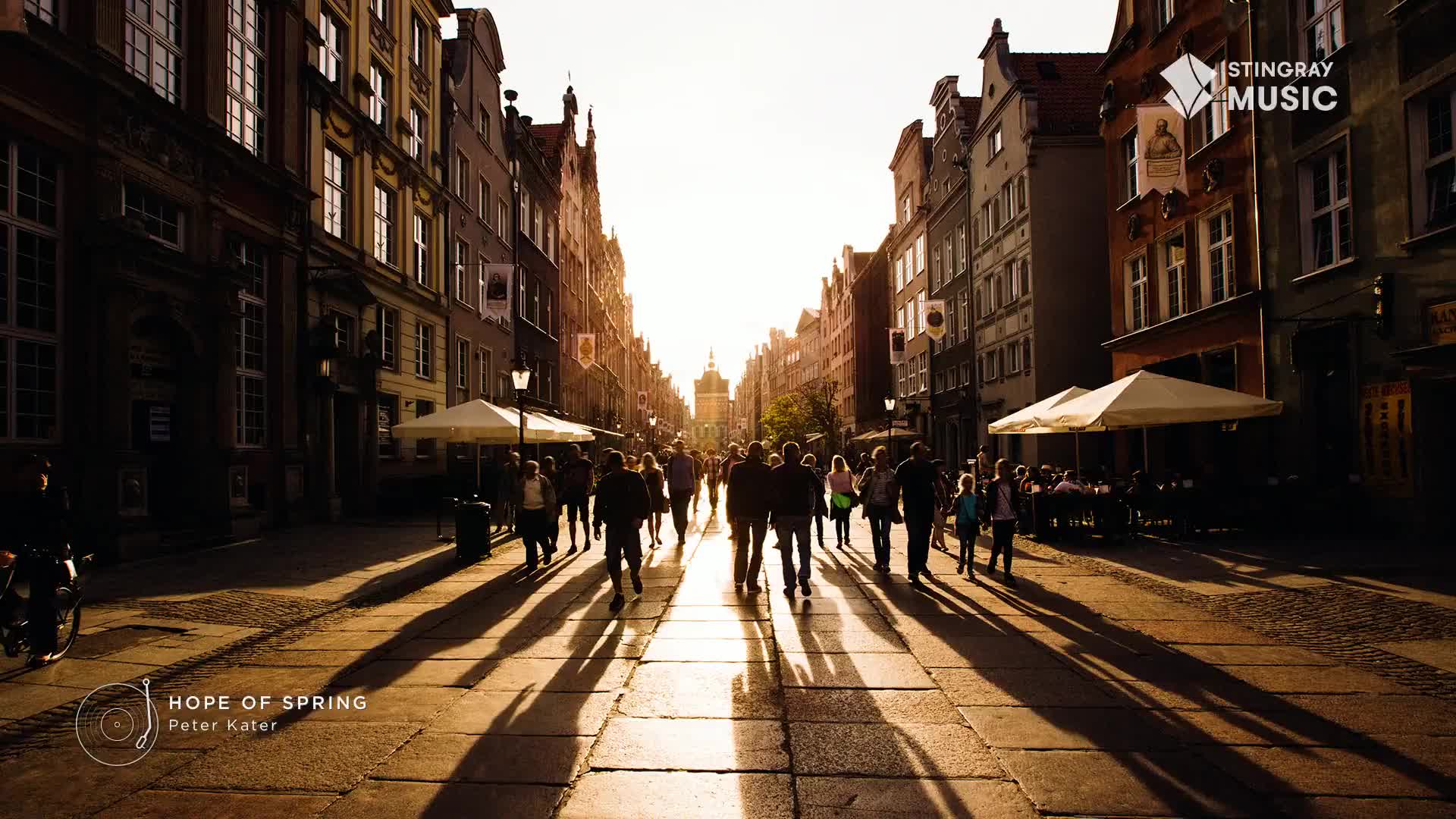 The setting sun casts long shadows down the cobblestone street as people stroll toward the distant building.  The Stingray Easy Listening logo, from Canada, is a nice touch for this scene of "Hope of Spring."

