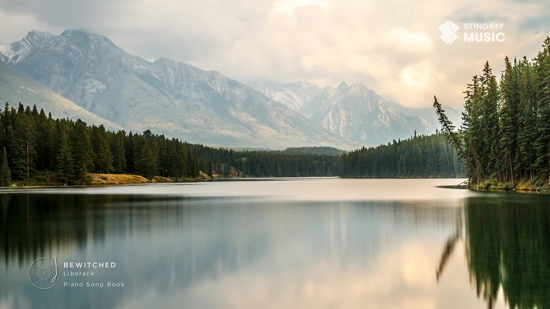 The still water mirrors the mountains and trees, creating a serene scene. The music from Stingray Easy Listening would fit perfectly with this Canadian landscape.
