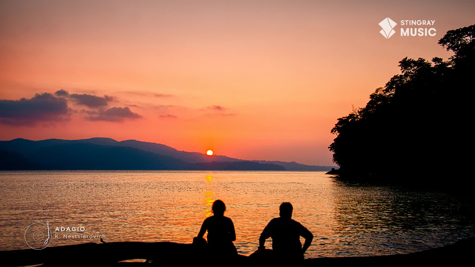 The sun, a fiery orb, dips towards the horizon, casting a warm glow over the water. Two figures sit silhouetted, enjoying the end of the day, perhaps listening to Stingray Easy Listening from Canada.
