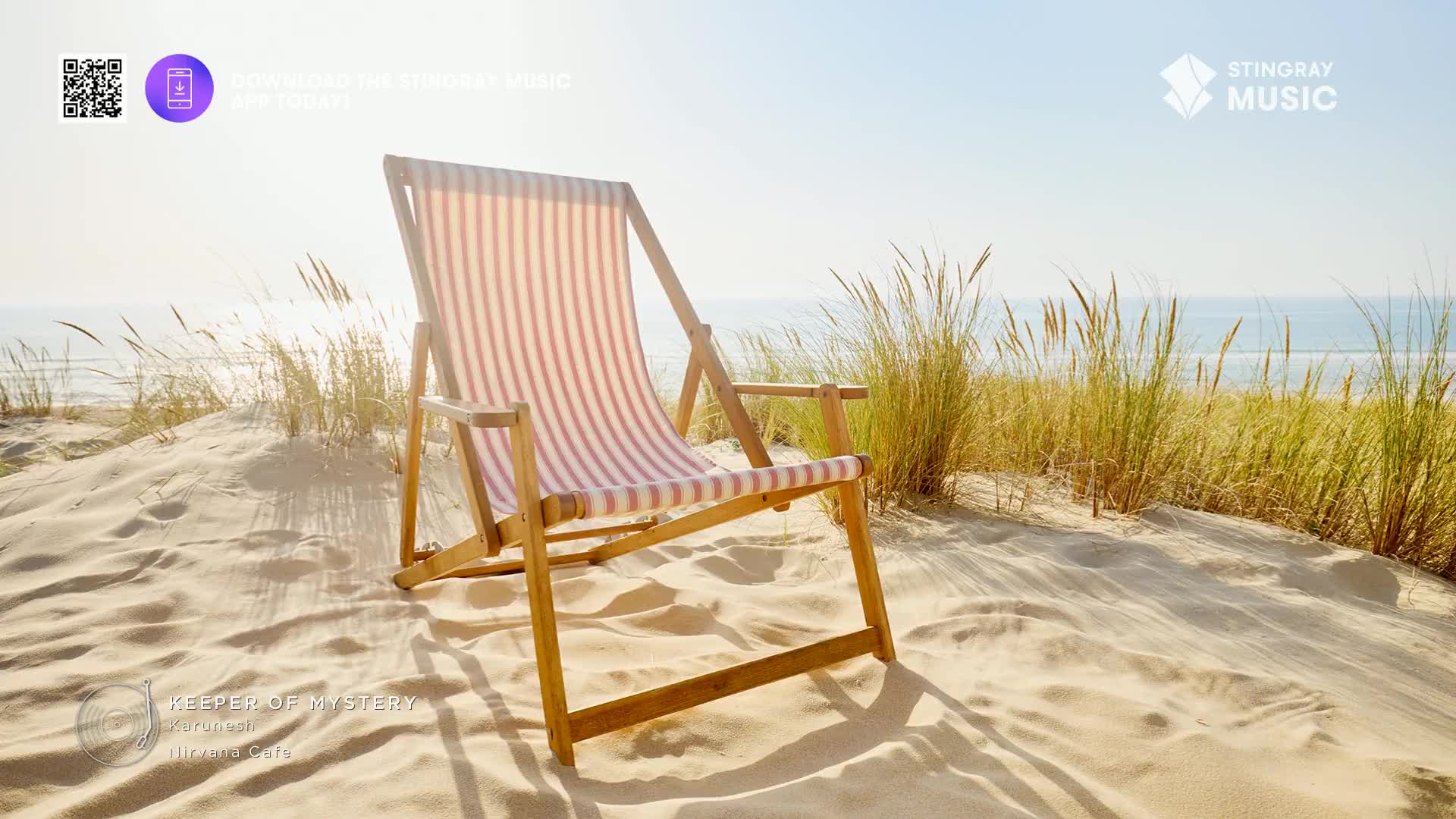 A striped beach chair sits open on a sandy dune, the sunlight catching the wood frame. Tall grasses sway gently in the breeze, and the ocean stretches out in the distance, promising a perfect day for a Stingray Easy Listening playlist from Canada.
