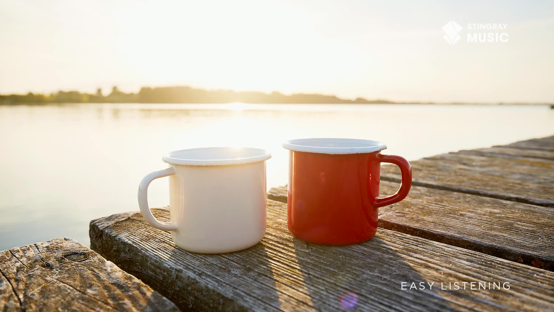 Two enamel mugs, one white and one red, sit on a weathered wooden dock, overlooking a calm body of water. The scene, bathed in the soft light of the Canadian sunrise, feels like a moment of peace, perfectly suited for Stingray Easy Listening.
Two enamel mugs, one white and one red, sit on a weathered wooden dock, overlooking a calm body of water. The scene, bathed in the soft light of the Canadian sunrise, feels like a moment of peace, perfectly suited for Stingray Easy Listening.