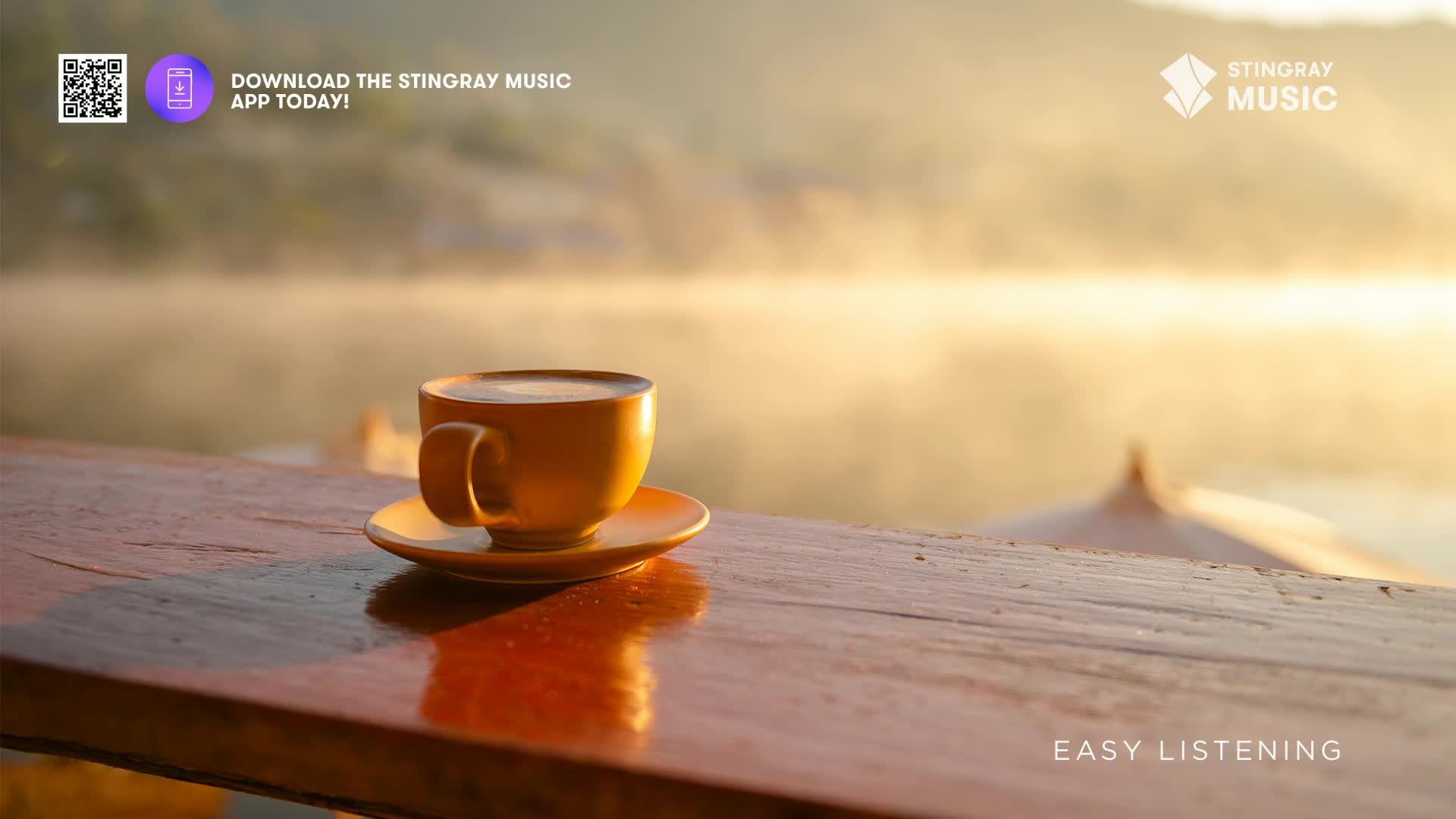 A steaming mug of coffee sits on a wooden table, catching the warm glow of early morning sun. Mist rises from the water behind it, painting the Canadian landscape in soft hues.