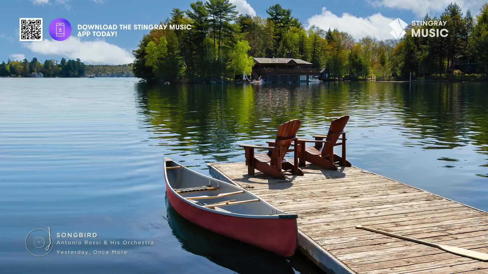 A red canoe rests beside a wooden dock, two Adirondack chairs waiting for company. The calm lake reflects the lush green trees and a distant cottage, a perfect scene for Stingray Easy Listening.
