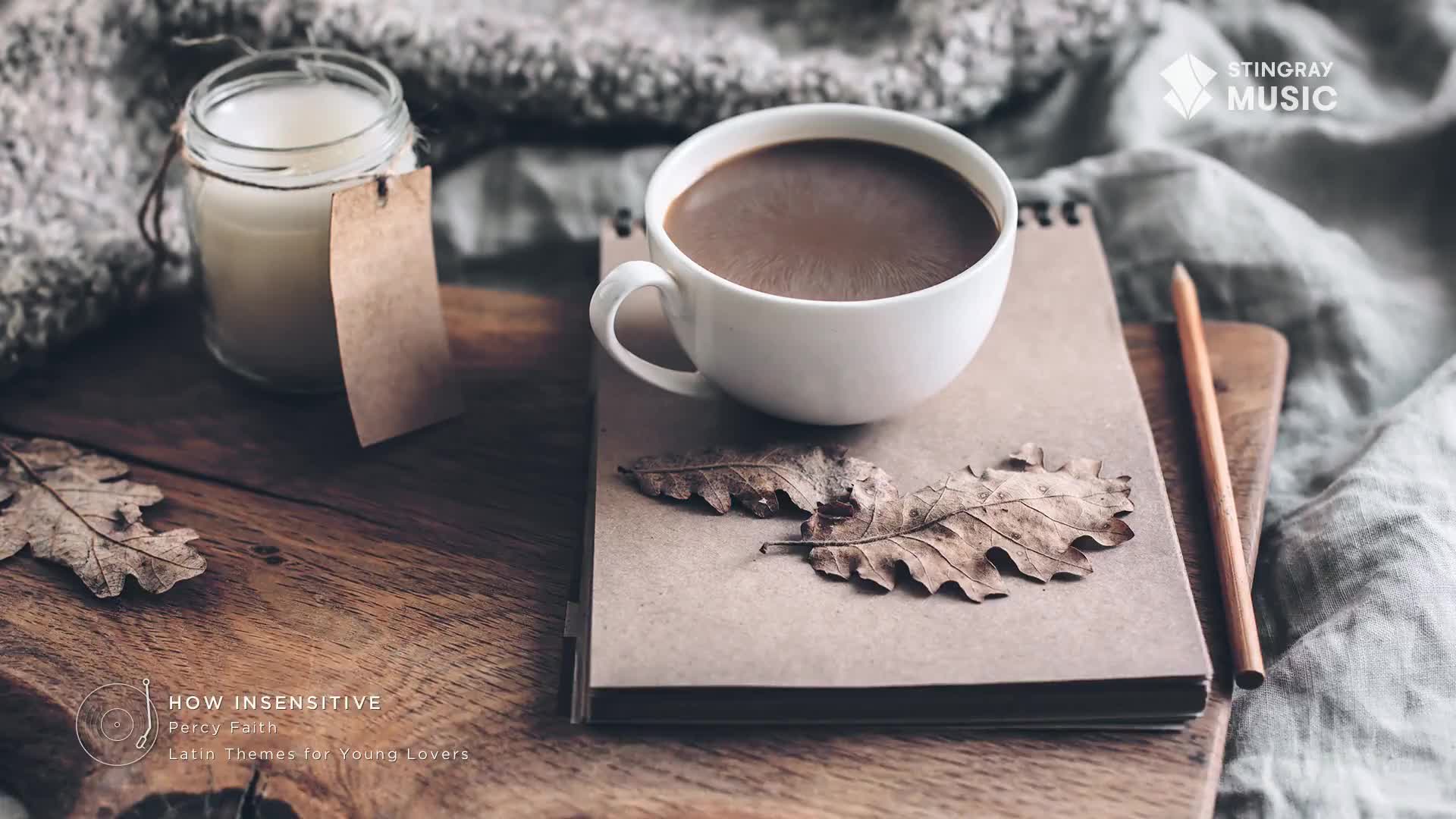 A steaming mug of coffee sits on a notebook, nestled amongst dried leaves. Beside it, a simple candle casts a soft glow, evoking a cozy Canadian autumn.