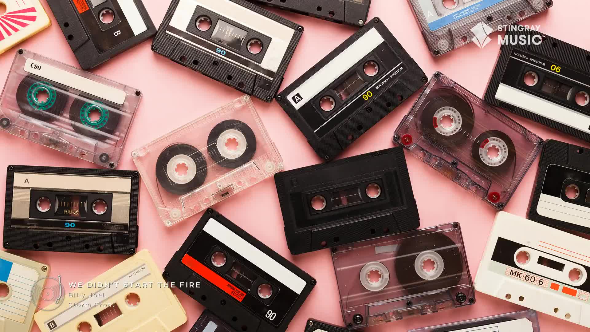 Cassette tapes of various colours and styles are scattered across a pink surface. The Stingray Music logo is visible, and the text "We Didn't Start the Fire" is displayed at the bottom left.
