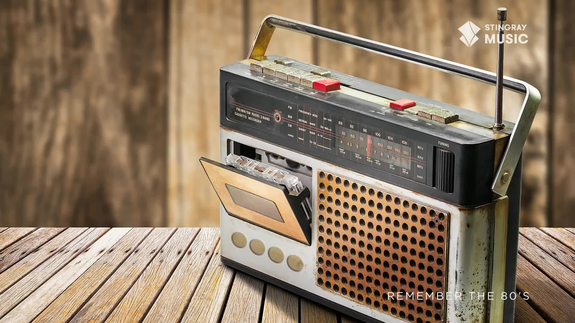 A vintage boombox sits on a wooden surface, its cassette door open with a tape partially ejected. The metallic radio is a relic, ready to play some tunes from Canada's Stingray Everything '80s.
