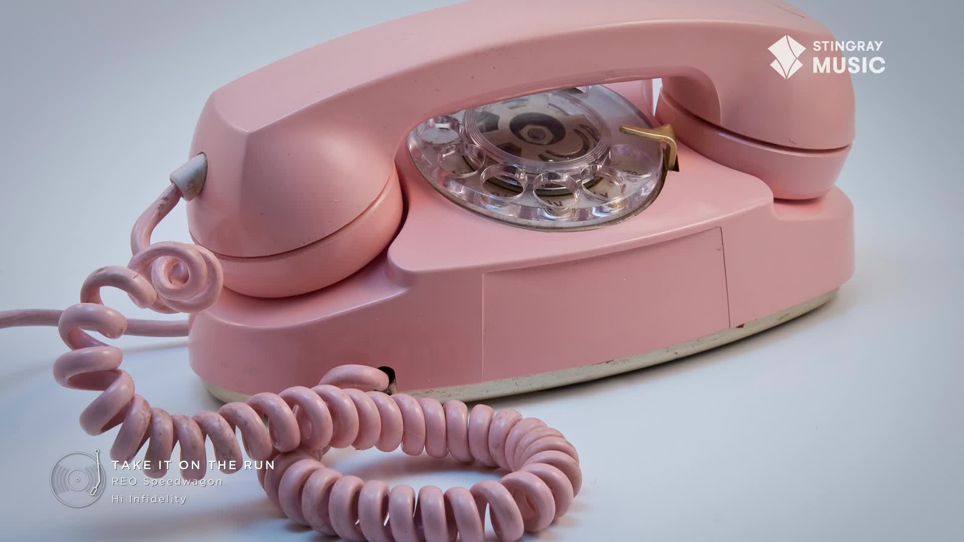 A vintage pink rotary phone sits on a white surface, its coiled cord snaking across the bottom. The Stingray Music logo is in the corner, and the image evokes a sense of nostalgia for the '80s in Canada.
