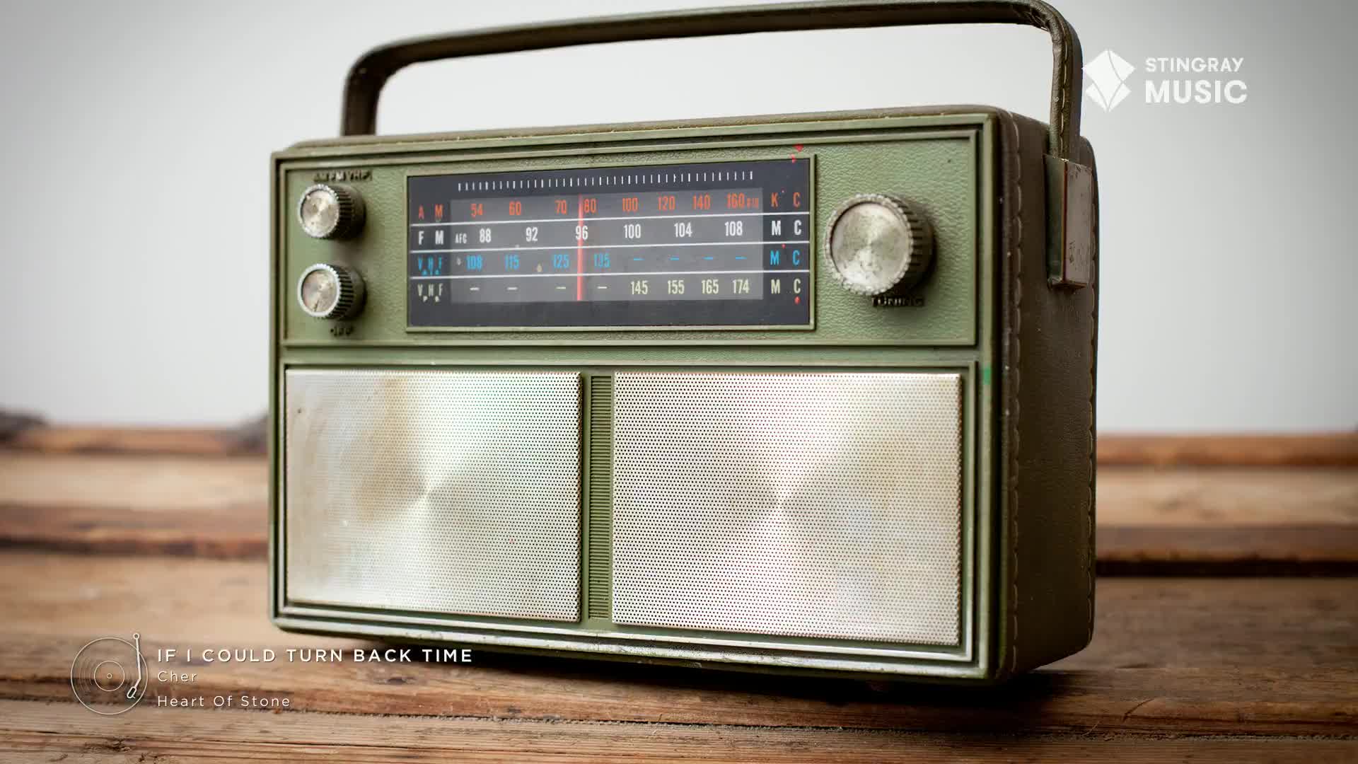 A vintage, olive-green radio sits on a wooden surface, ready to play some tunes. The dial is set to 96, maybe a station from Canada, broadcasting the '80s hits from Stingray Everything.
