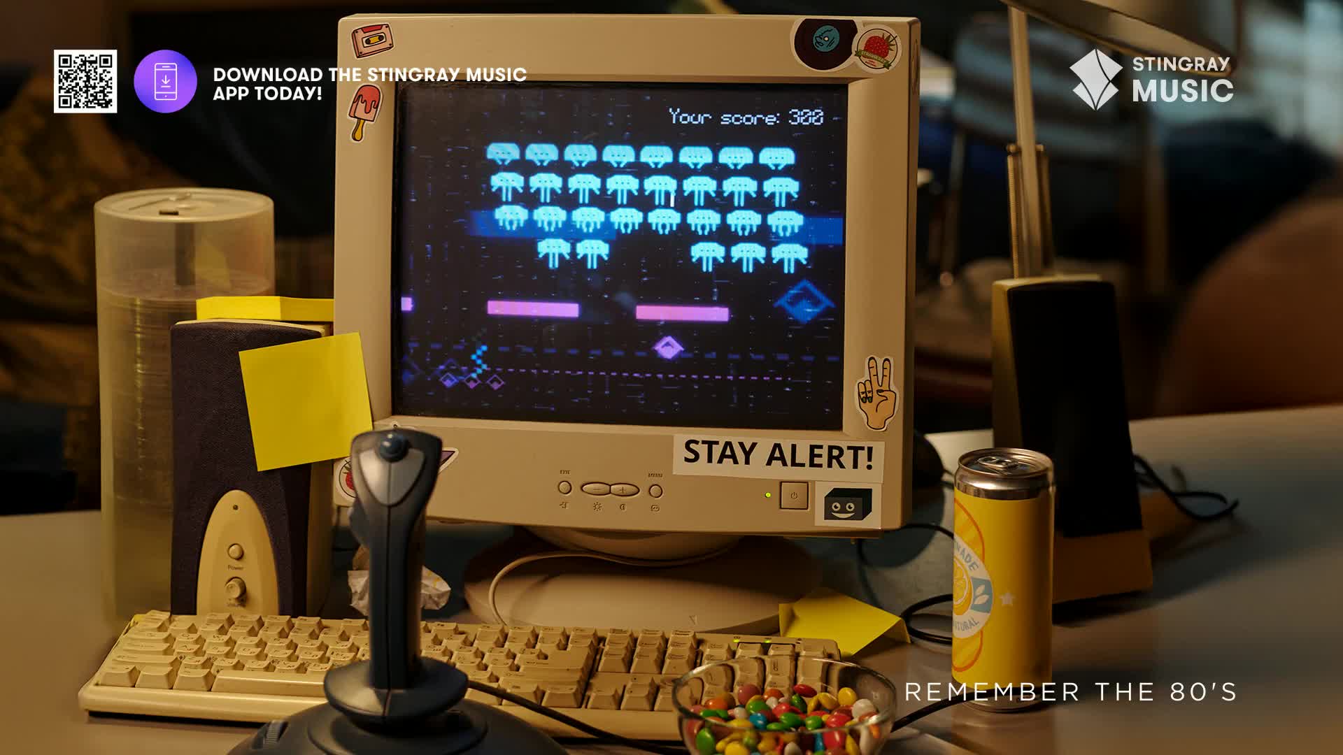 A vintage computer monitor displays a retro video game, with pixelated aliens descending. A joystick and keyboard sit nearby, evoking the era of Stingray Everything '80s and the Canadian nostalgia it represents.
