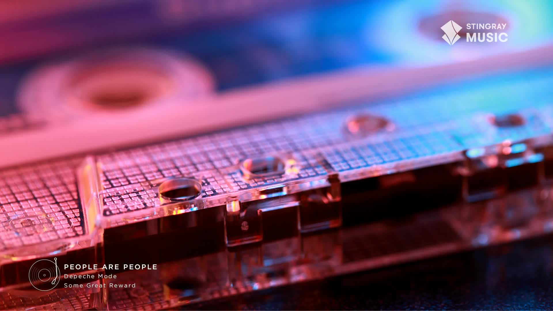 A cassette tape, likely from Canada's Stingray Music, sits bathed in pink and blue light. The clear plastic casing reveals the tape spools and the grid pattern of the magnetic tape itself.
