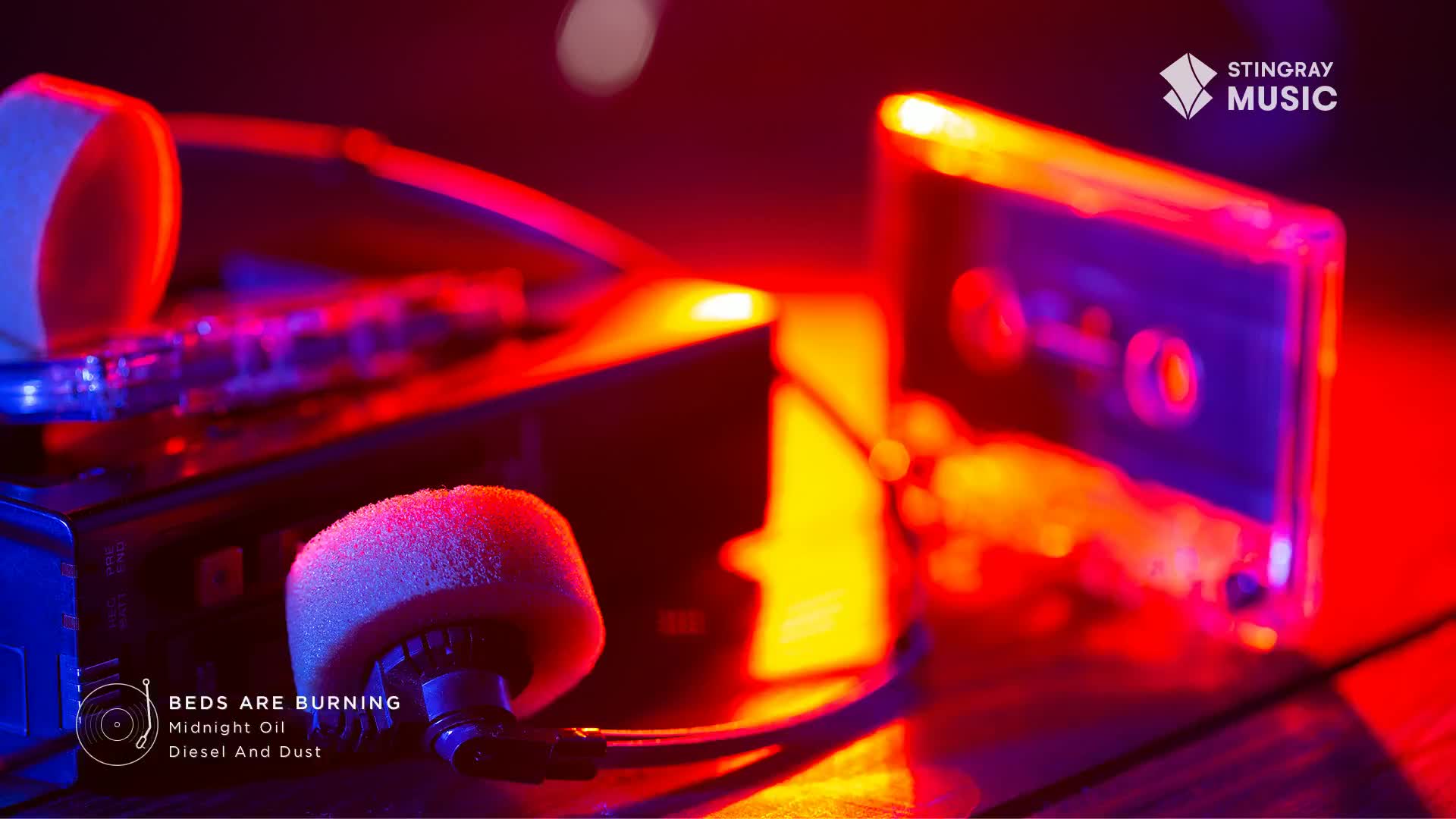 A cassette tape sits next to a portable player, bathed in the vibrant glow of red and blue lights. The iconic sound of Midnight Oil's "Beds Are Burning" is about to fill the air, a true taste of Canadian Everything '80s. A cassette tape sits next to a portable player, bathed in the vibrant glow of red and blue lights. The iconic sound of Midnight Oil's "Beds Are Burning" is about to fill the air, a true taste of Canadian Everything '80s.