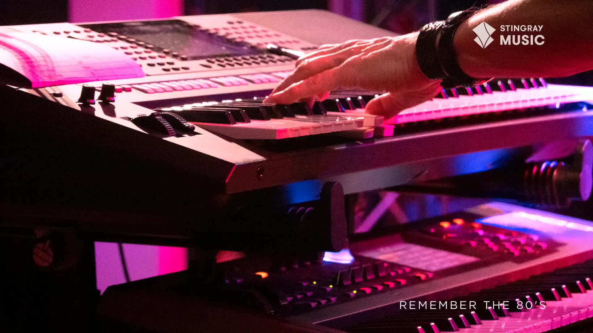 A hand dances across the keys of a synthesizer, bathed in the neon glow of a Canadian stage. The sound, a throwback to the '80s, fills the air as another keyboard sits below, ready for the next chord.