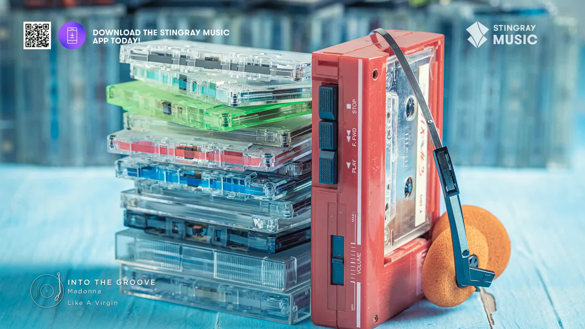A stack of colourful cassette tapes sits beside a red portable player with orange headphones. The player's tape deck is open, revealing a cassette with the label "Into the Groove" by Madonna.