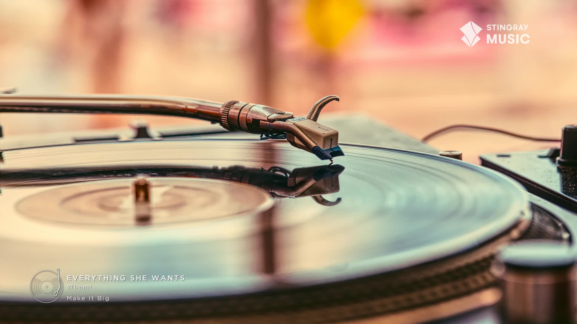 The tonearm of a turntable rests on a spinning vinyl record, its needle poised to play "Everything She Wants" by Make It Big. The warm, hazy background suggests an outdoor summer gathering, perhaps a Canadian music festival.