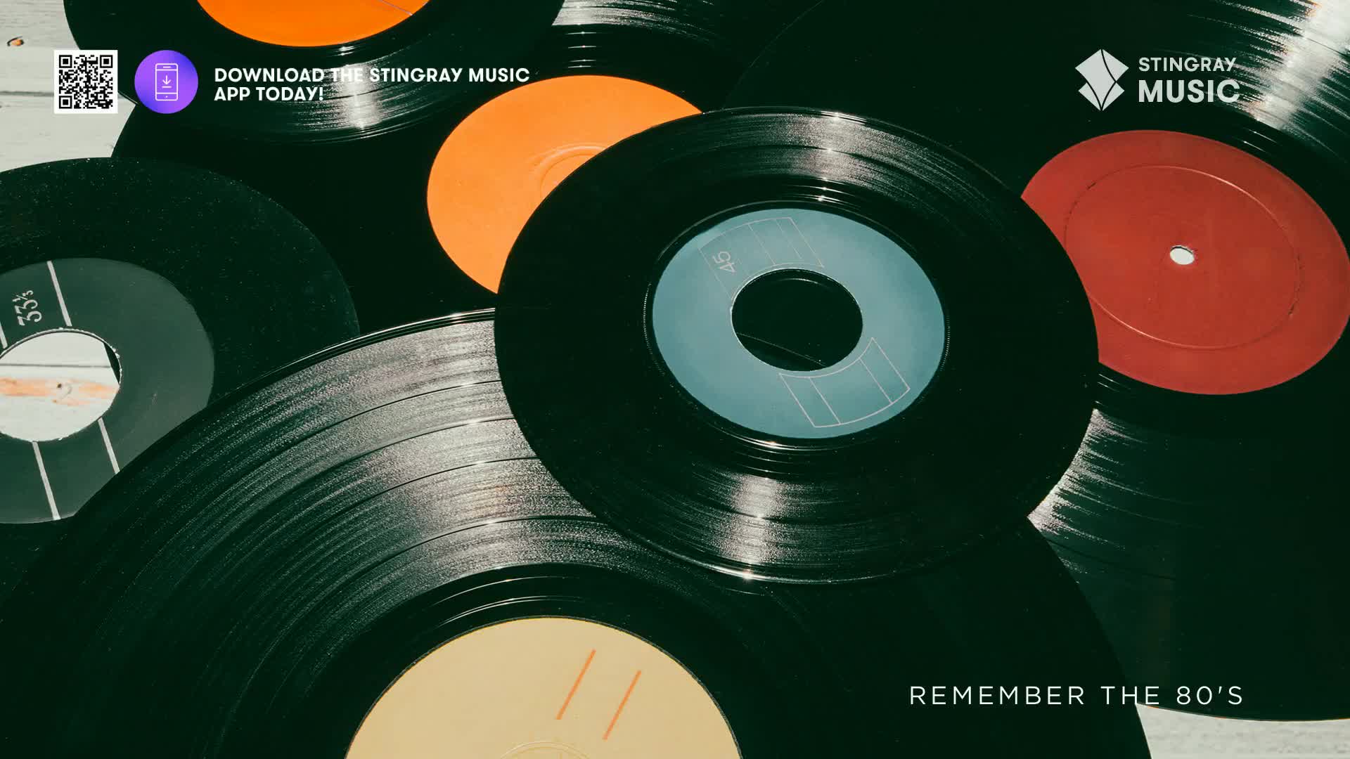 A stack of vinyl records, some with vibrant orange and red labels, are arranged in a close-up shot. The grooves of the black discs catch the light, hinting at the music of the 80s.