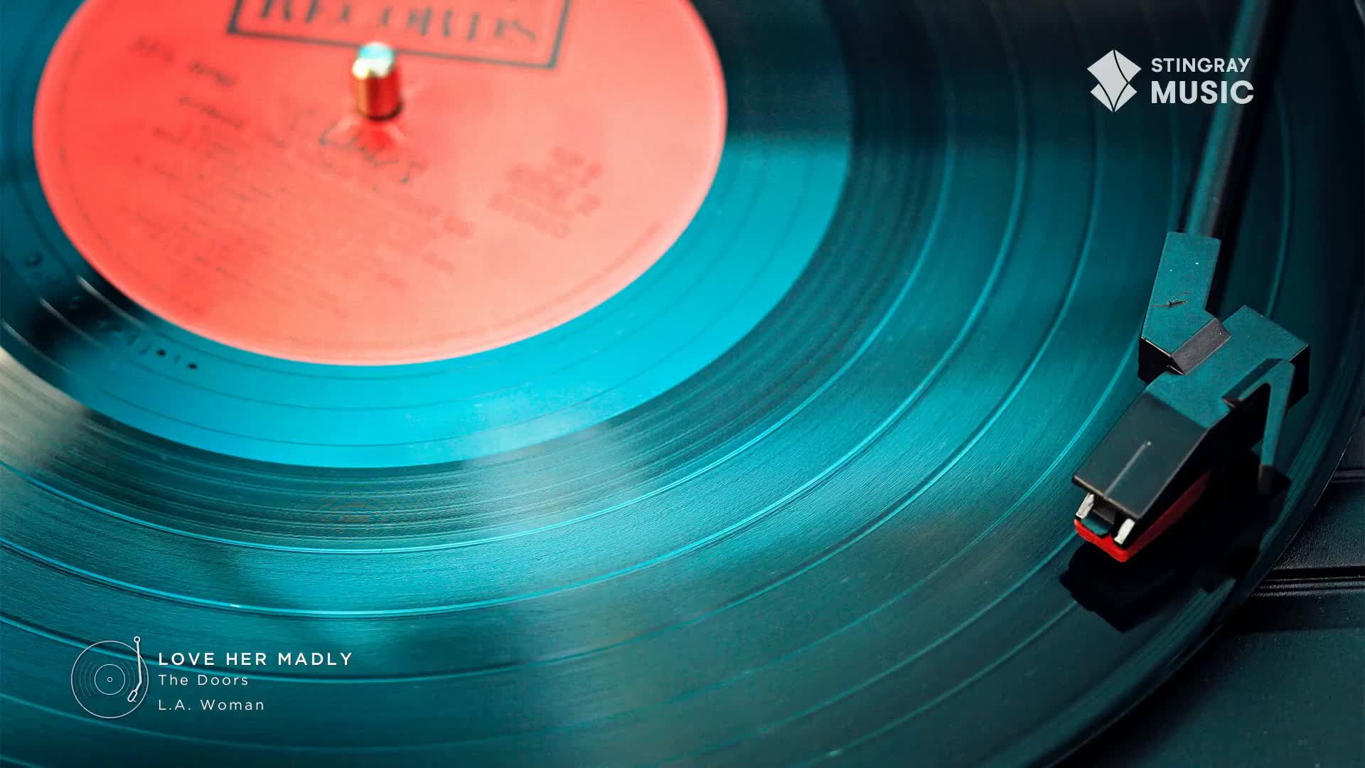 A record spins, the needle resting in its grooves, as "Love Her Madly" by The Doors plays on Stingray Flashback 70's, a Canadian music channel. The vinyl's teal surface reflects the light.
