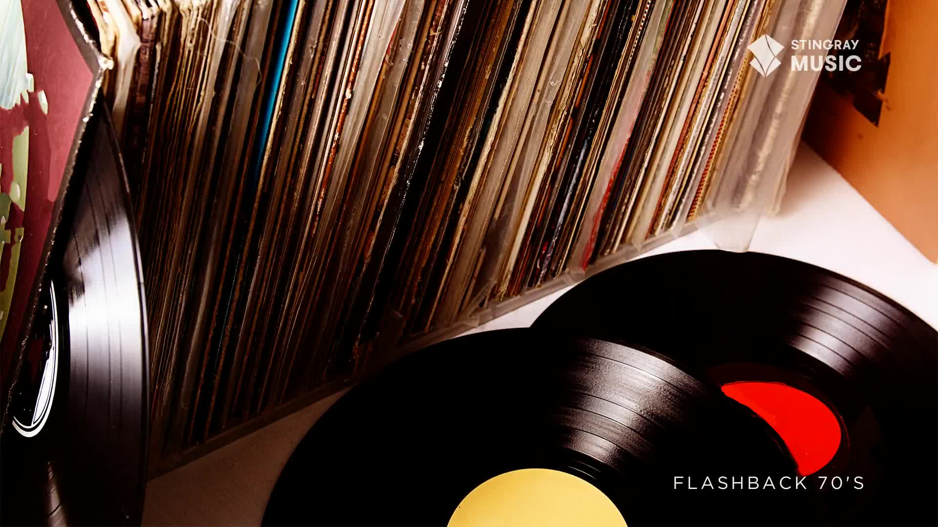 A stack of vinyl records, some with red labels, sits in front of a collection of albums. The Stingray Flashback 70's logo is visible.

