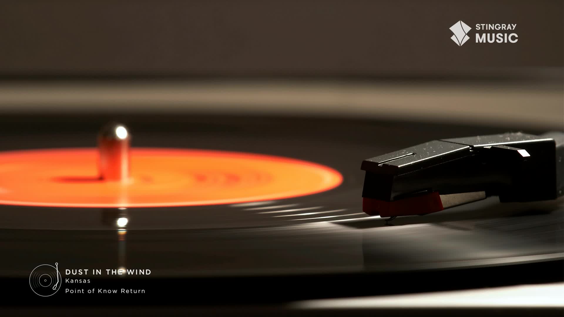 The needle rests on a spinning vinyl record, ready to play "Dust in the Wind" from the Stingray Flashback 70's channel. The orange label of the record is lit by a warm glow.
