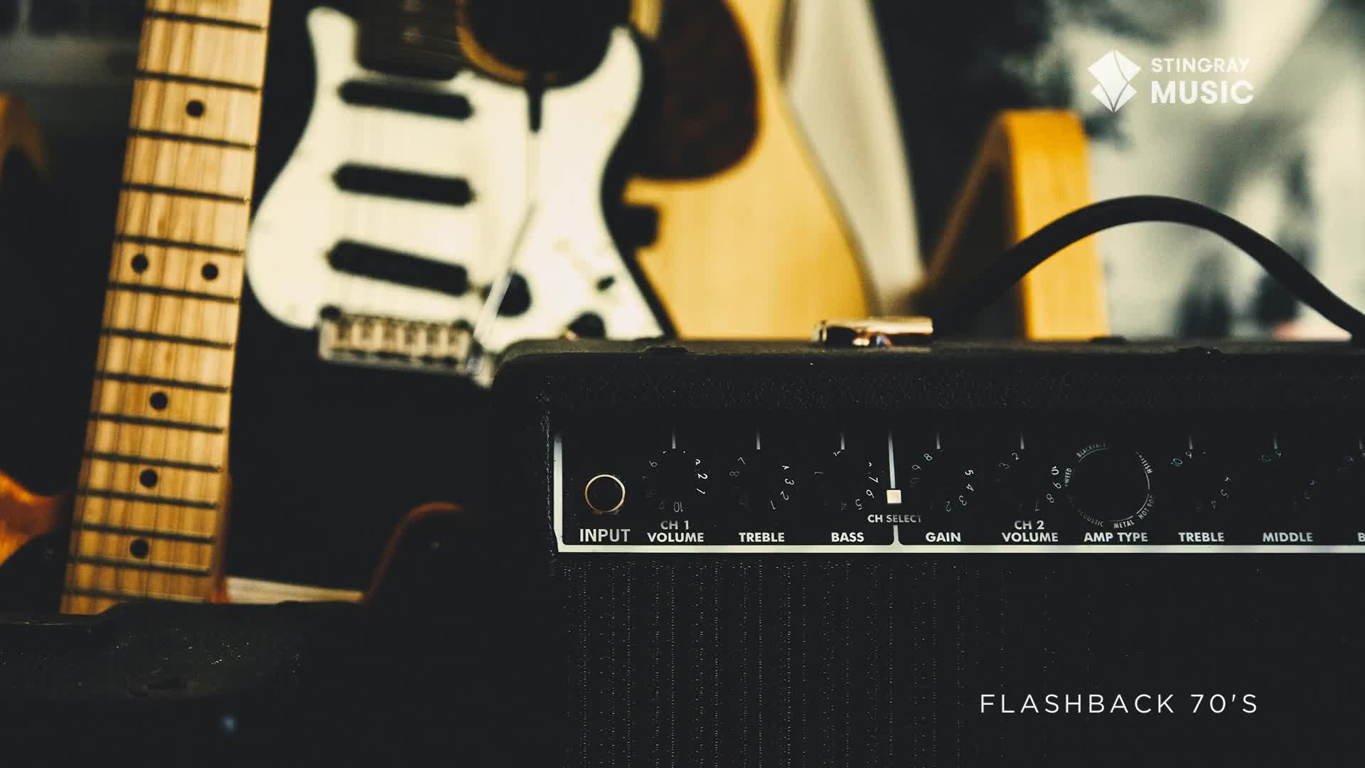 The black amplifier, labeled "Flashback 70's" by Stingray Music Canada, sits in the foreground, its knobs and input jack clearly visible. Behind it, the necks of guitars lean against each other, ready to be played.
The black amplifier, labeled "Flashback 70's" by Stingray Music Canada, sits in the foreground, its knobs and input jack clearly visible. Behind it, the necks of guitars lean against each other, ready to be played.