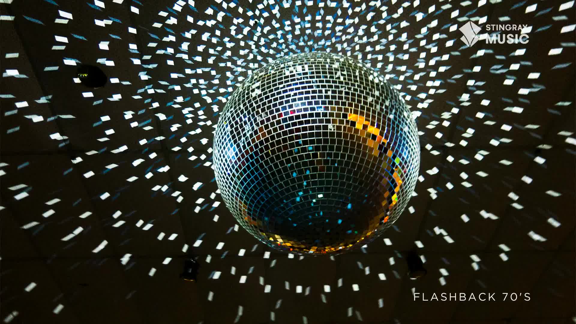 A mirrored disco ball spins, casting a constellation of bright squares across the dark ceiling. This is pure 70s Canada, a flashback to the dance floor.