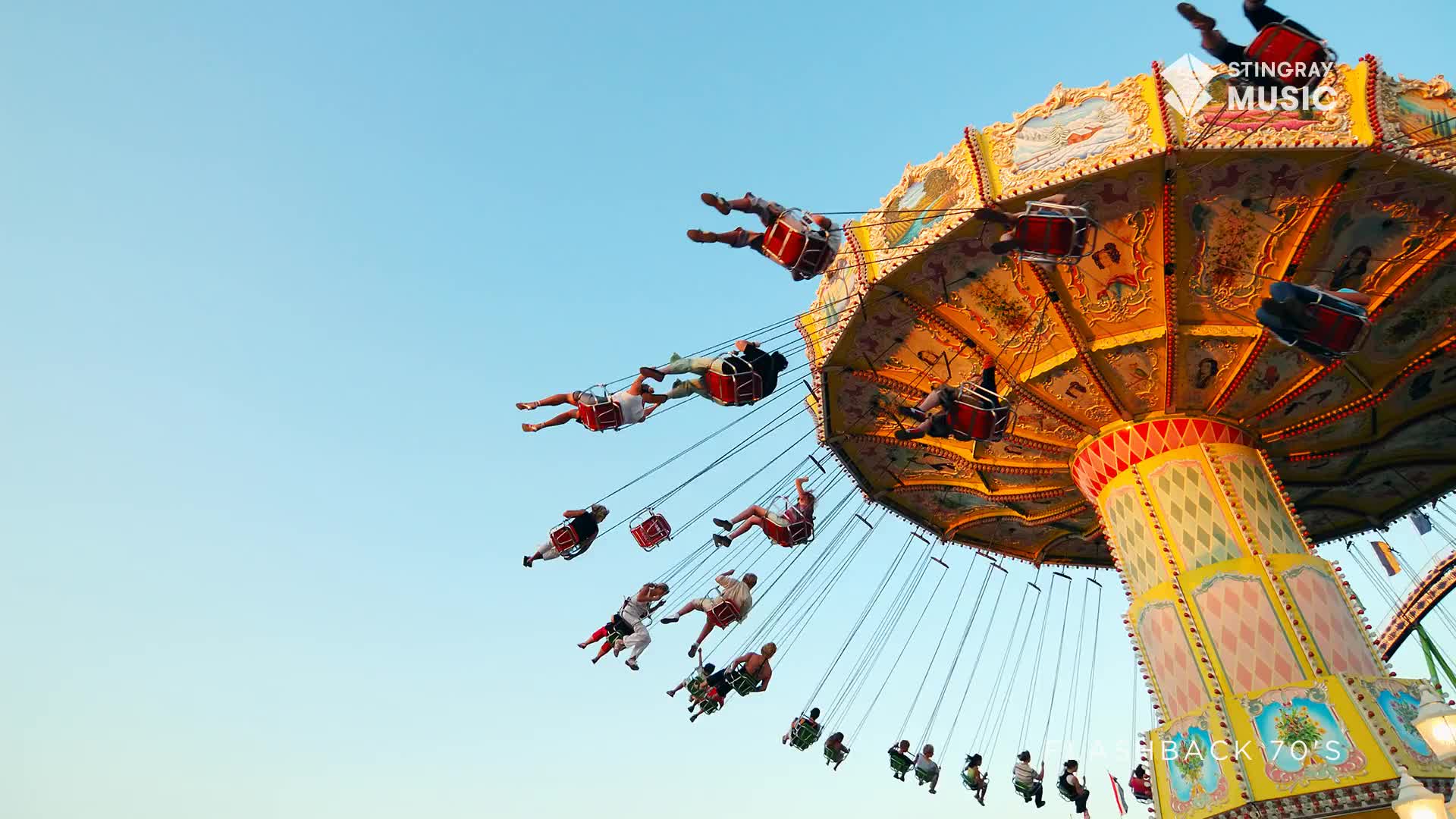 The swing ride is spinning fast, lifting people high into the bright Canadian sky. Their legs dangle as they arc outwards, a classic summer scene.