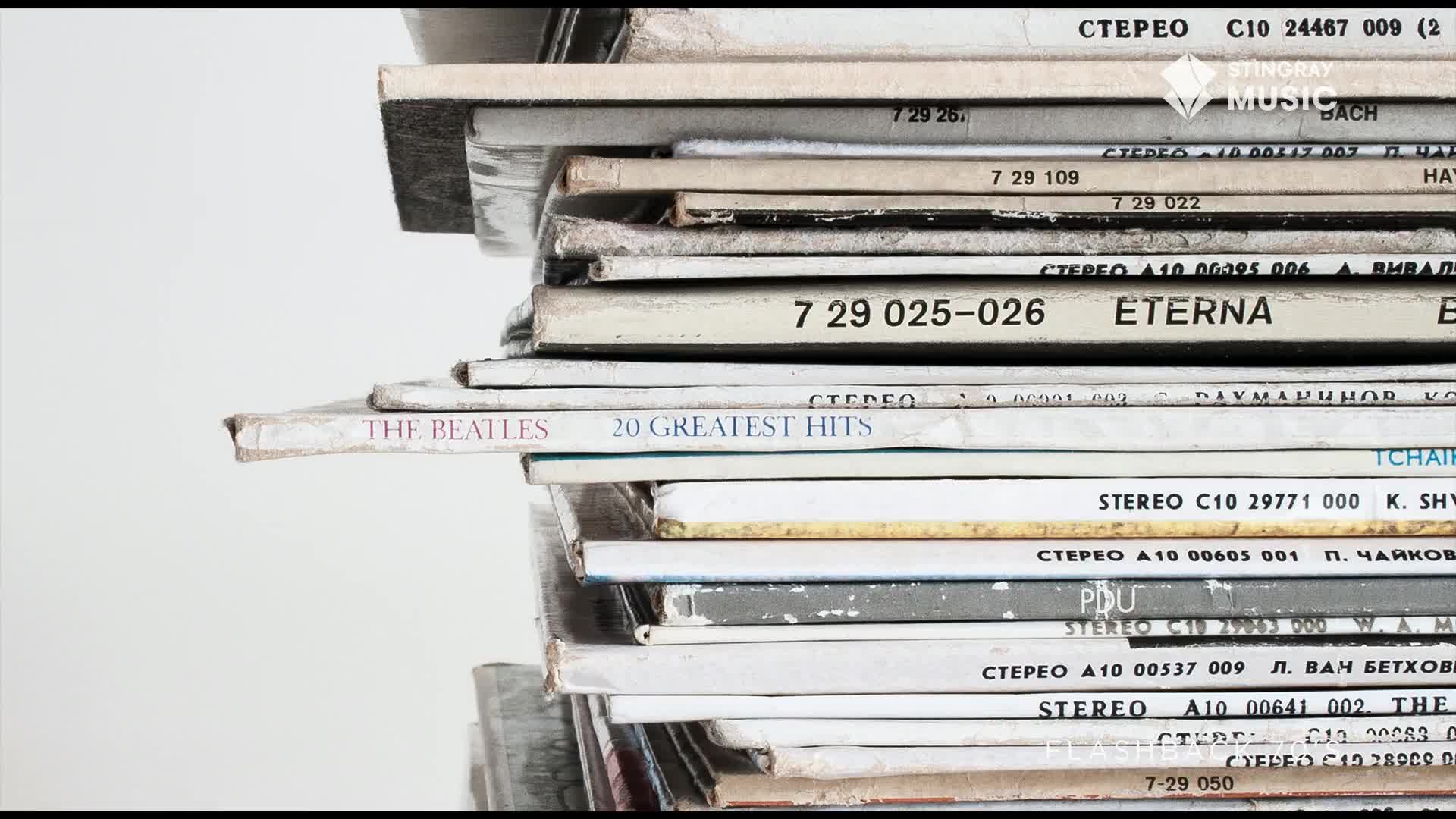 A stack of vinyl records leans precariously, the spine of "The Beatles: 20 Greatest Hits" jutting out. The worn cardboard sleeves hint at countless spins, a tangible echo of 70s Canadian music scenes.