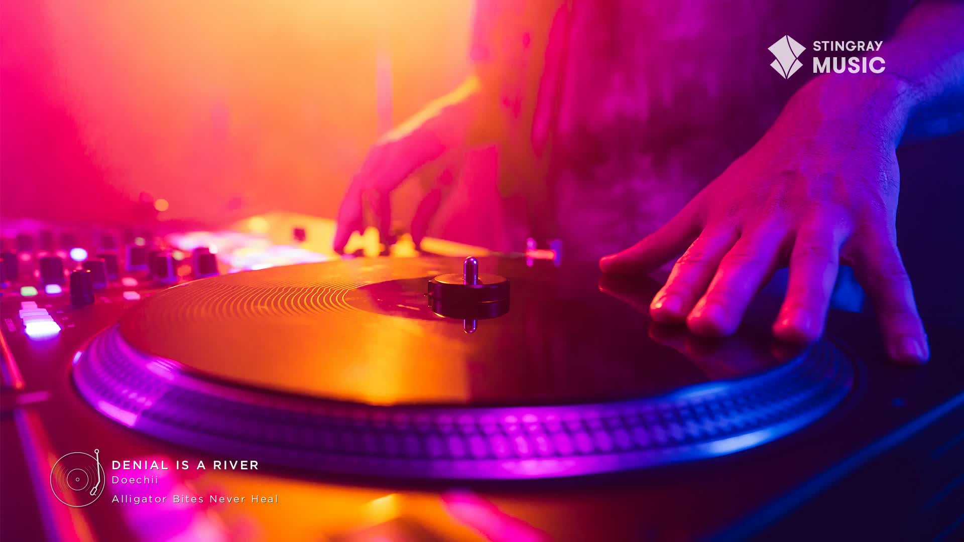 A hand hovers over a spinning record, the surface reflecting the neon lights of the Stingray Hit List show. The turntable is the focus, with the artist's touch ready to shape the music.
