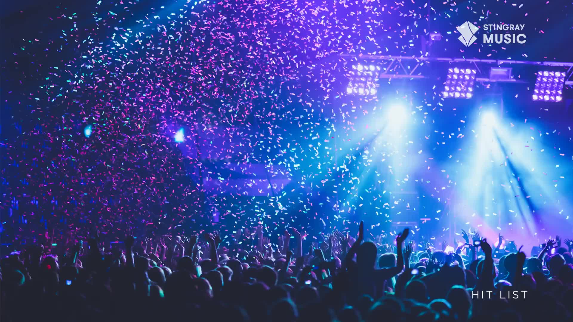 Confetti rains down on the crowd, illuminated by bright stage lights. People are raising their arms, lost in the music of the Stingray Hit List show.

