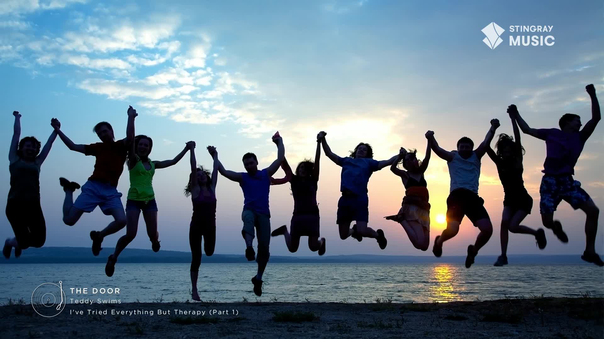 A group of people, holding hands, are suspended mid-air against a sunset over the water.  They're silhouetted, part of a scene that could be on Canada's Stingray Hit List.
